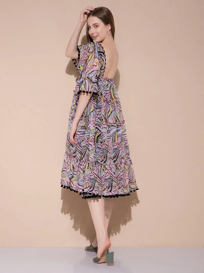 Woman wearing colorful abstract print midi dress with puff sleeves and open back, standing on light gray floor