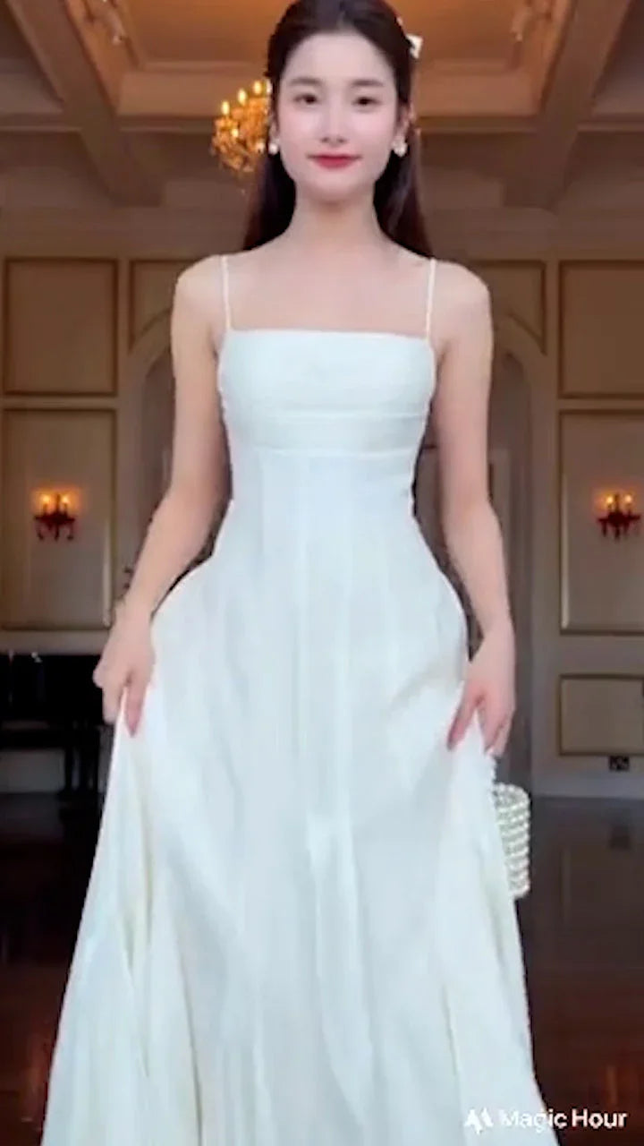 Woman wearing elegant white sleeveless flared maxi dress in a classic room with chandelier
