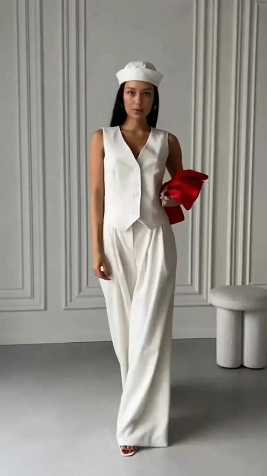 Woman wearing a white sleeveless waistcoat with matching wide-leg pants and white beret, holding red fabric