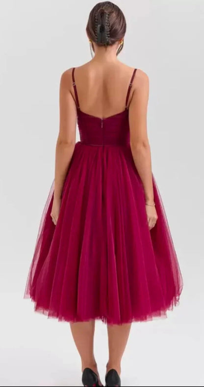 Woman wearing a burgundy tulle midi dress with spaghetti straps, back view on gray background